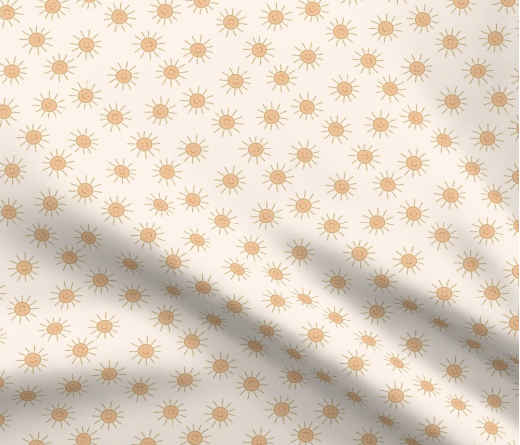 cream colored fabric patterned with smiling yellow suns